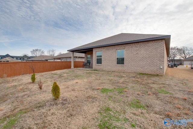 rear view of house featuring brick siding and fence