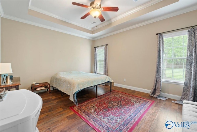 bedroom with a tray ceiling, wood-type flooring, ornamental molding, baseboards, and a ceiling fan