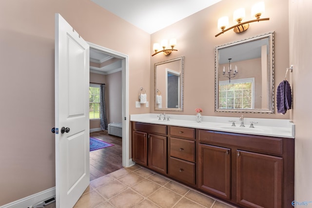 bathroom with double vanity, crown molding, and baseboards