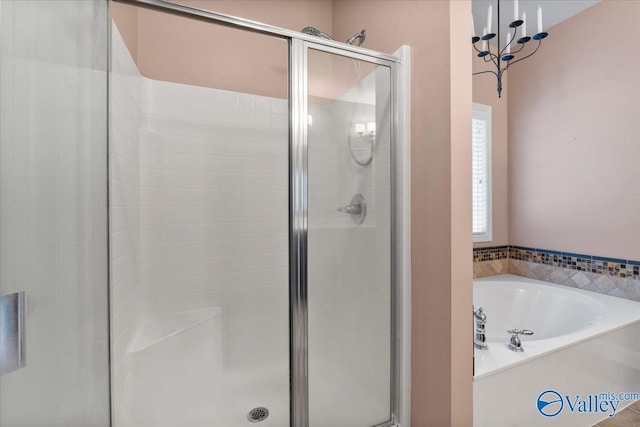 full bath with a bath, a stall shower, and a chandelier