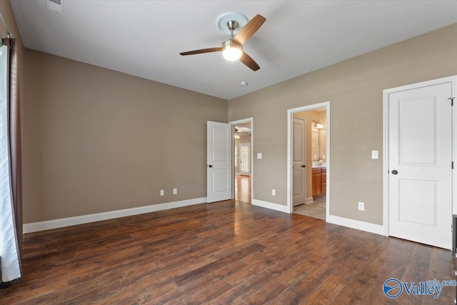 unfurnished bedroom featuring wood finished floors, baseboards, connected bathroom, and a ceiling fan