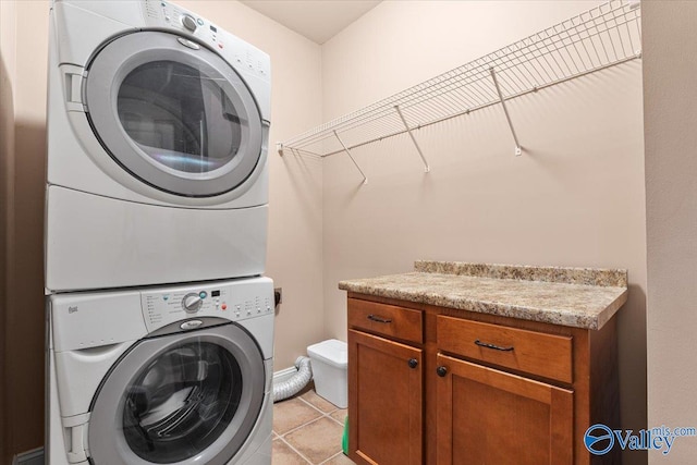 laundry room with stacked washer and clothes dryer and light tile patterned flooring
