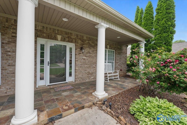 entrance to property with covered porch and brick siding