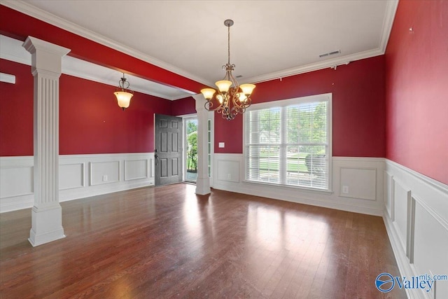 unfurnished dining area with ornate columns, wood finished floors, a wainscoted wall, a chandelier, and a decorative wall