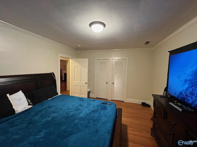 bedroom with a textured ceiling, dark hardwood / wood-style floors, and crown molding