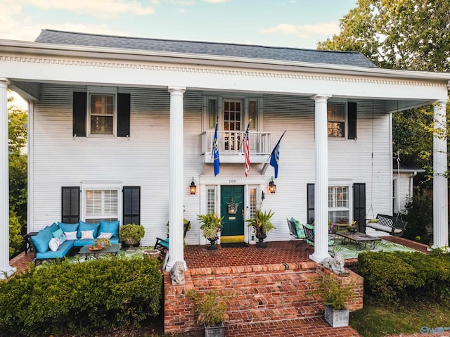 greek revival inspired property featuring a porch and a shingled roof