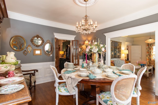 dining area with a notable chandelier, dark wood finished floors, crown molding, and wainscoting