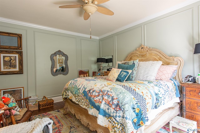 bedroom featuring ornamental molding, wood finished floors, a ceiling fan, and a decorative wall