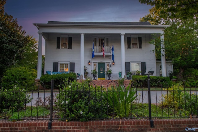 neoclassical / greek revival house featuring a fenced front yard and a balcony