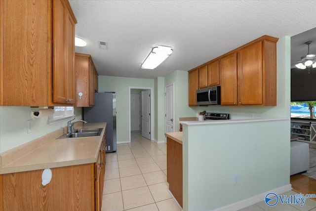 kitchen featuring sink, light tile patterned floors, stainless steel appliances, and a textured ceiling