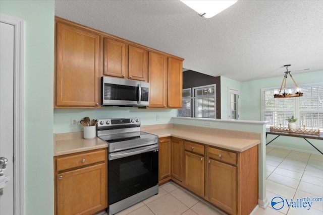 kitchen with stainless steel appliances, pendant lighting, light tile patterned floors, and kitchen peninsula