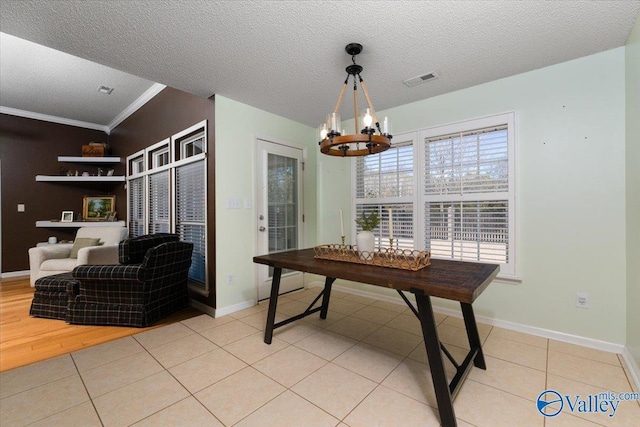 dining area featuring light tile patterned flooring, ornamental molding, a notable chandelier, and a textured ceiling