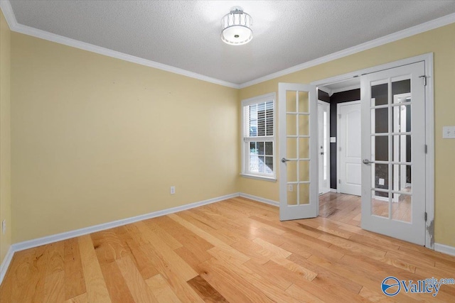 empty room featuring hardwood / wood-style flooring, crown molding, a textured ceiling, and french doors