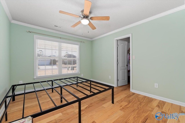 bedroom featuring ornamental molding, ceiling fan, a textured ceiling, and light hardwood / wood-style flooring