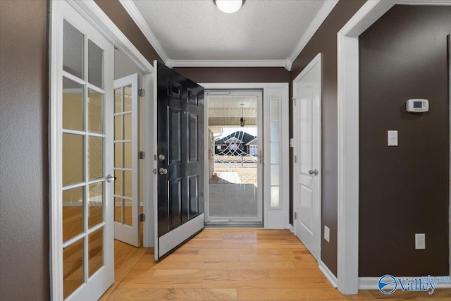 entryway with french doors, ornamental molding, light hardwood / wood-style flooring, and a textured ceiling