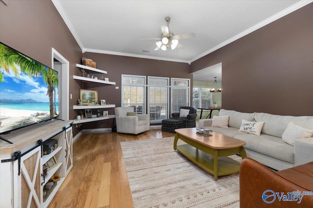 living room with crown molding, ceiling fan with notable chandelier, and light hardwood / wood-style flooring