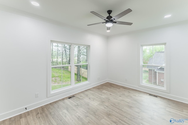 empty room with baseboards, visible vents, and light wood finished floors