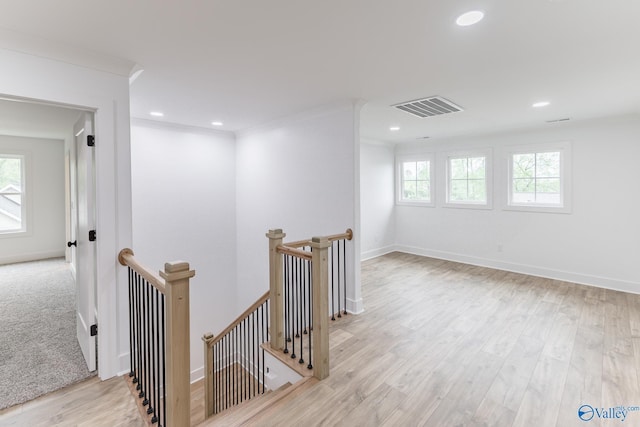 corridor with recessed lighting, visible vents, ornamental molding, an upstairs landing, and wood finished floors