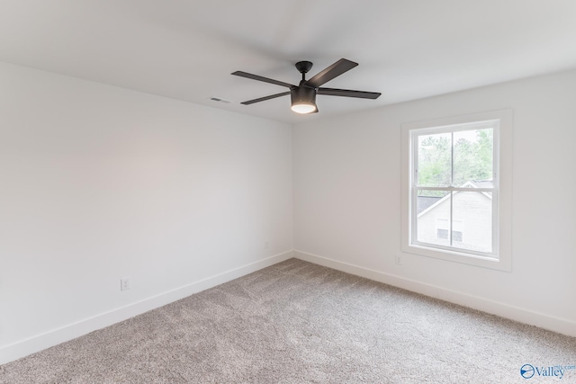 empty room with carpet floors, visible vents, ceiling fan, and baseboards