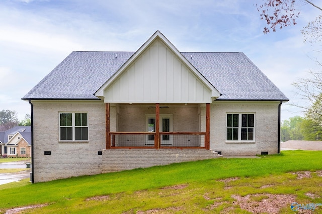 back of property with a yard and brick siding