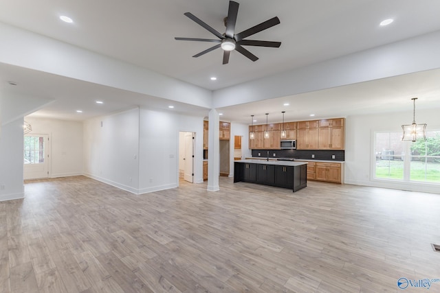 interior space featuring light wood-type flooring, open floor plan, and stainless steel microwave