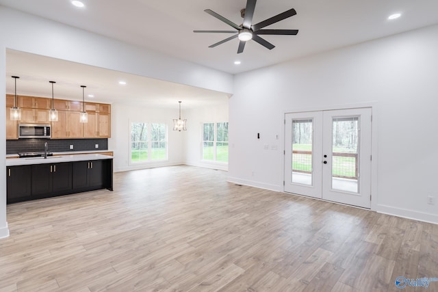 unfurnished living room featuring light wood-type flooring, french doors, a sink, and recessed lighting