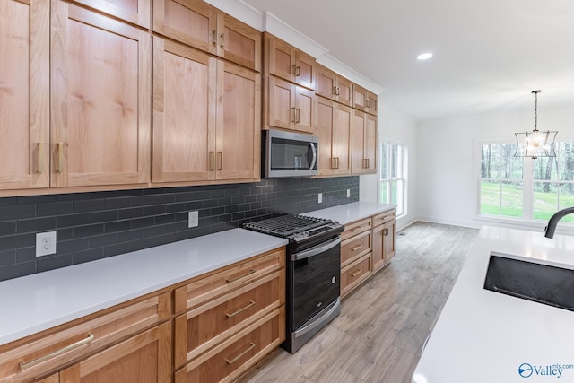 kitchen with light wood finished floors, tasteful backsplash, light countertops, stainless steel microwave, and gas stove