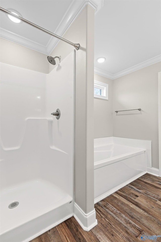 bathroom with a bath, hardwood / wood-style flooring, and ornamental molding