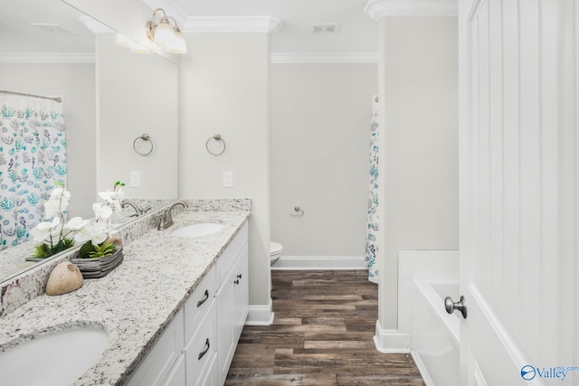 bathroom with a bathtub, hardwood / wood-style flooring, ornamental molding, vanity, and toilet