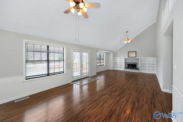 unfurnished living room featuring ceiling fan, high vaulted ceiling, a fireplace, dark hardwood / wood-style flooring, and french doors