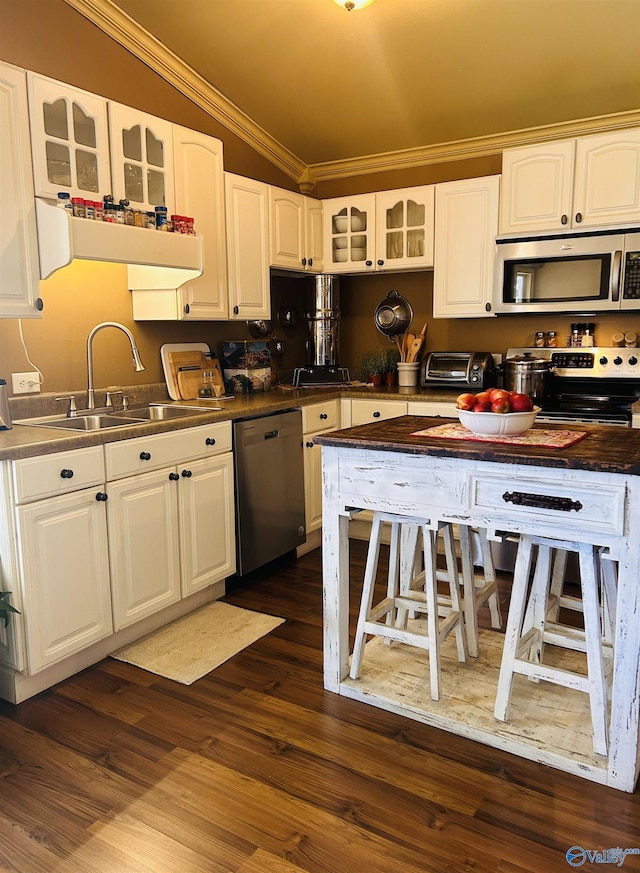 kitchen with a sink, white cabinets, ornamental molding, appliances with stainless steel finishes, and glass insert cabinets