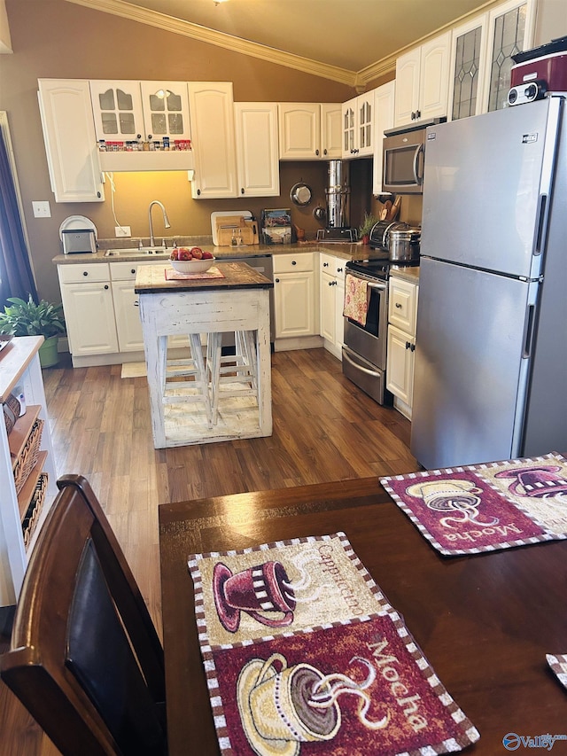 kitchen featuring glass insert cabinets, lofted ceiling, white cabinets, and stainless steel appliances