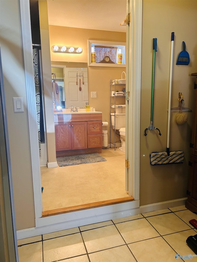 bathroom featuring tile patterned flooring, baseboards, vanity, and toilet