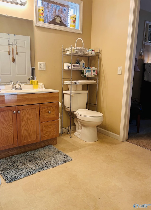 half bathroom featuring toilet, vanity, and baseboards