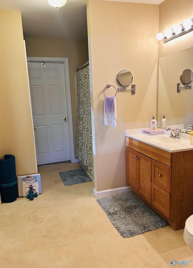 bathroom featuring a shower with shower curtain, baseboards, vanity, and toilet