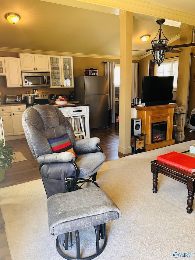 living area with ornamental molding, dark wood finished floors, and a glass covered fireplace