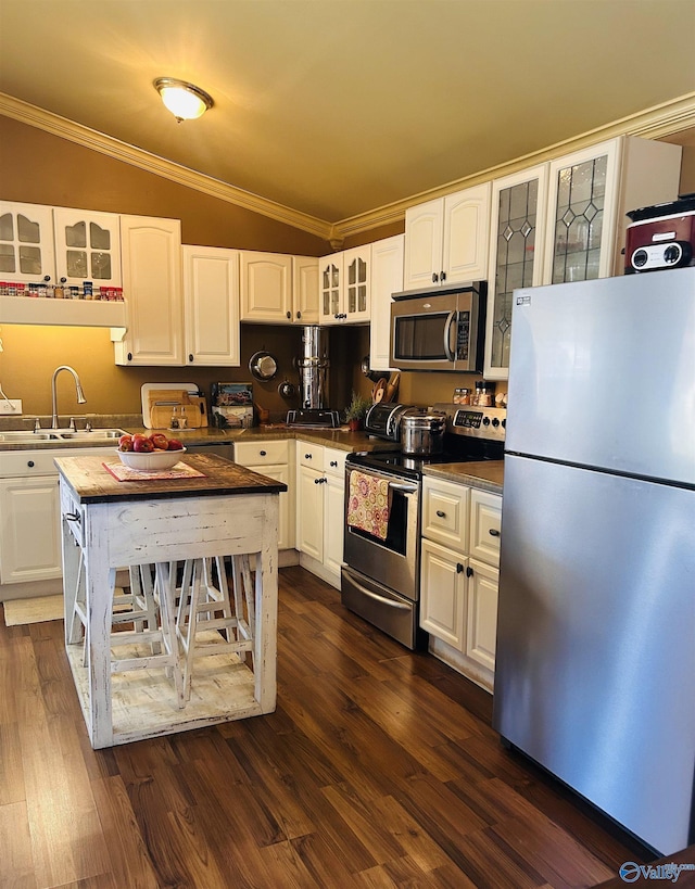 kitchen featuring white cabinets, dark wood finished floors, glass insert cabinets, appliances with stainless steel finishes, and ornamental molding