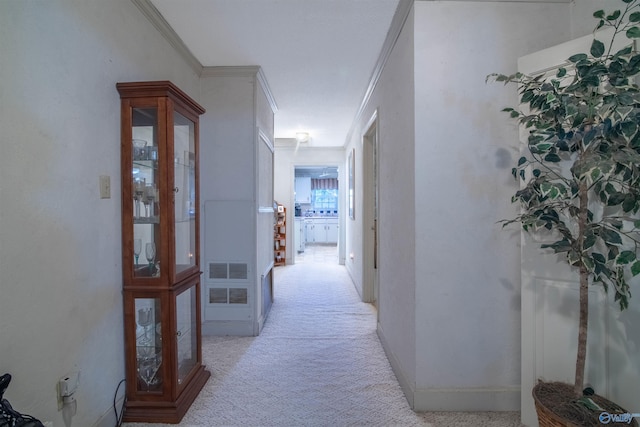 hallway with ornamental molding and light carpet