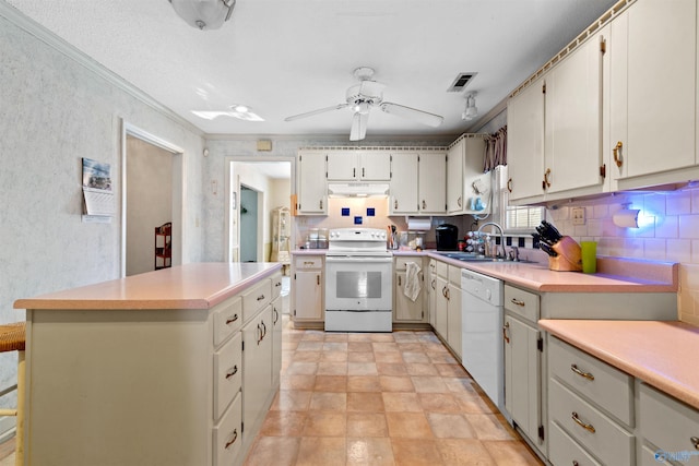 kitchen with a center island, white appliances, backsplash, sink, and ceiling fan