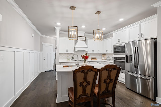 kitchen featuring a breakfast bar, white cabinetry, decorative light fixtures, an island with sink, and stainless steel appliances