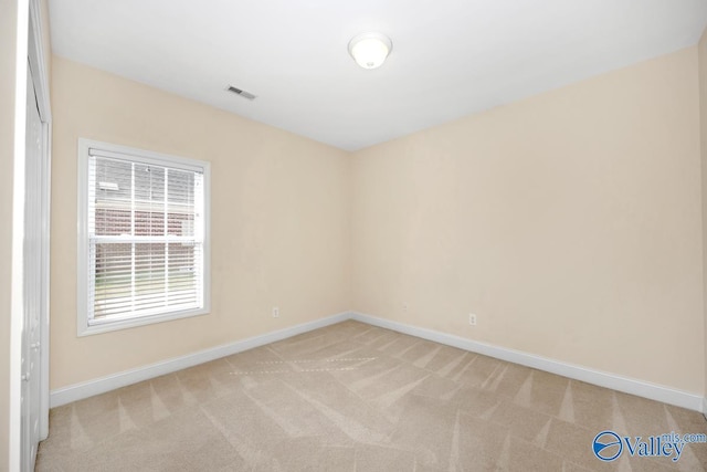 empty room featuring visible vents, baseboards, and light carpet