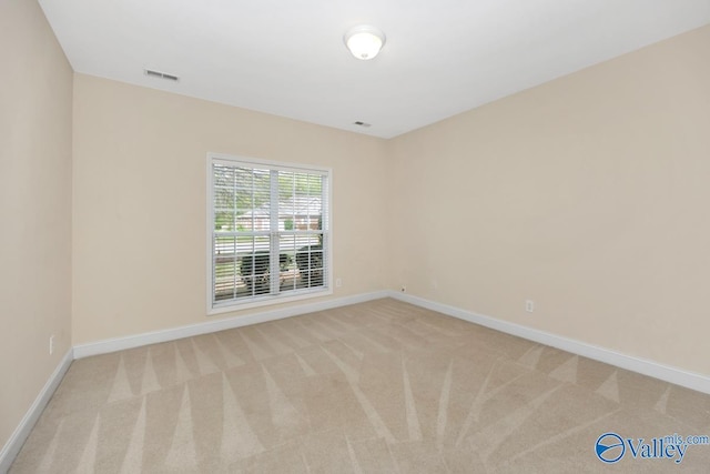 spare room with light carpet, baseboards, and visible vents