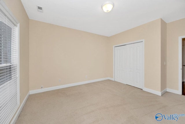 unfurnished bedroom featuring light carpet, baseboards, and a closet