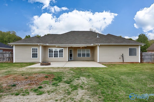 back of property with a yard, a patio area, a fire pit, fence, and a shingled roof