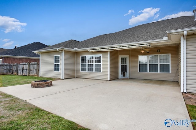 back of property with a lawn, an outdoor fire pit, a patio, fence, and a shingled roof
