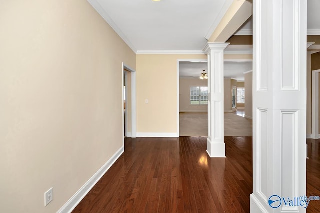 corridor with dark wood-style flooring, baseboards, ornate columns, and crown molding
