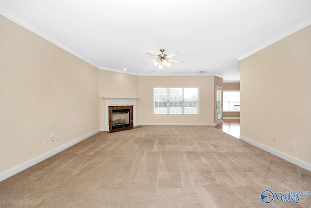 unfurnished living room with crown molding, ceiling fan, light colored carpet, a tile fireplace, and baseboards