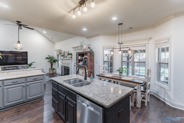 kitchen with ceiling fan, a kitchen island with sink, dishwasher, a sink, and dark wood-type flooring