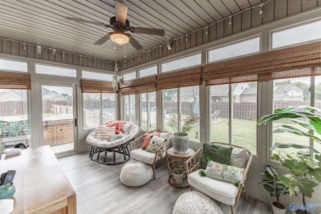 sunroom with a hot tub, a water view, and a ceiling fan