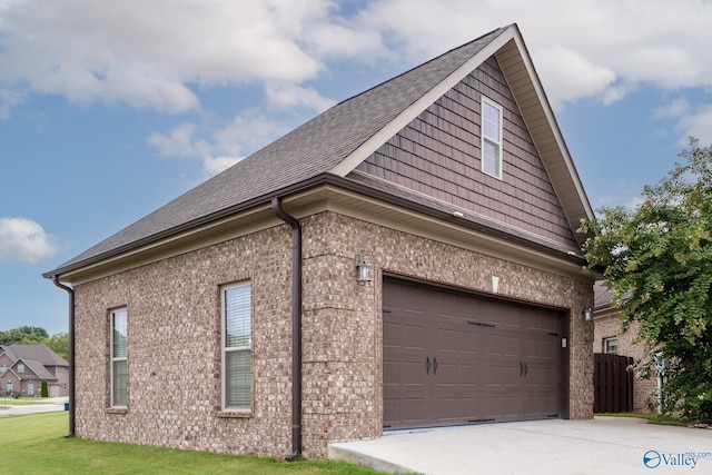 view of side of property featuring brick siding, a shingled roof, a garage, and concrete driveway